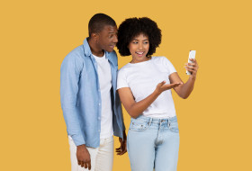 African American woman smiling and showcasing something on her smartphone screen