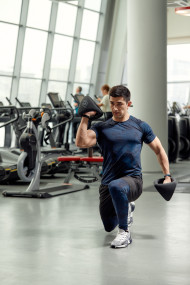 Athletic man shakes his biceps with dumbbell in his hands. Healthy lifestyle concept