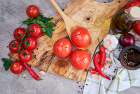 blanched tomatoes on wooden cutting board ready for peeling at domestic kitchen