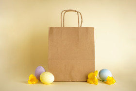 Easter eggs and paper bag on yellow background