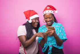 excited black female friends holding cellphones recommending app