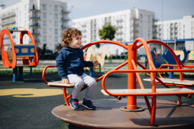 Hilarious little boy in an empty playground during quarantine without protection