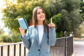 young pretty woman holding passport outdoors intending realizes